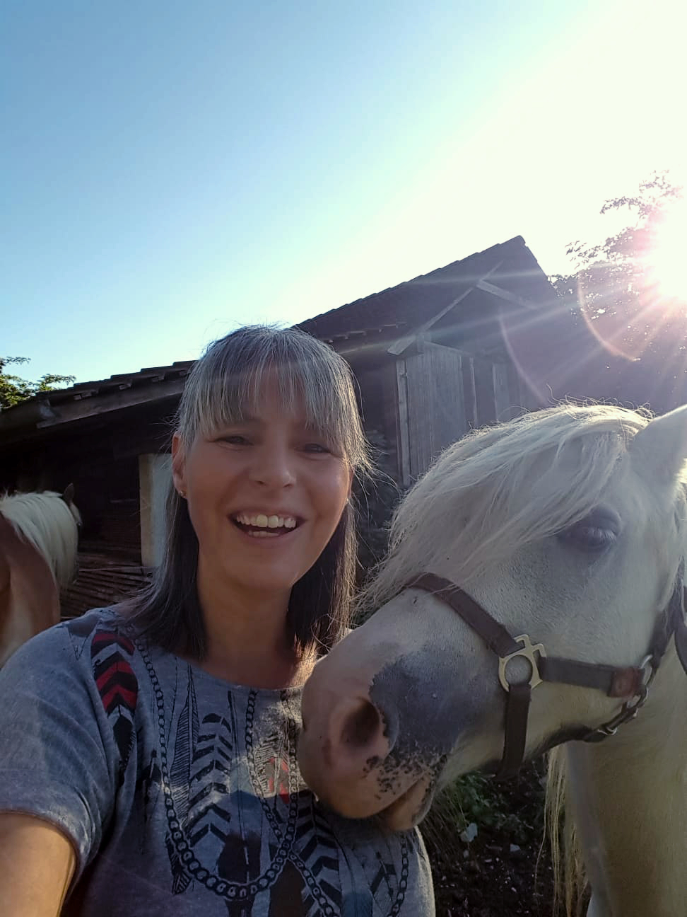 Andrea lächelt mit ihrem Welsh-Pony Cindy in der Abendsonne – aufgebautes Vertrauen