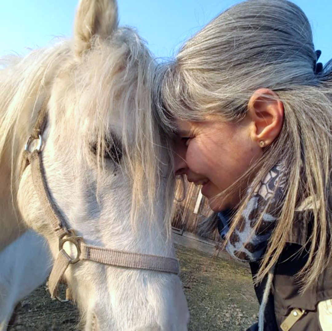 Andrea lehnt vertrauensvoll Stirn an Stirn mit ihrem Welsh-Pony Cindy