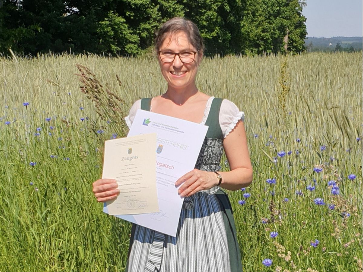 Jasmin Rogatsch hält ihren Facharbeiterbrief Pferdewirtschaft im Kornfeld